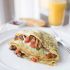 Cheesy egg “crepes” with crispy pancetta, sausage, gruyere cheese, diced tomato and chives