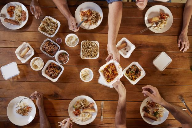 Reaching to get something on the other side of the table