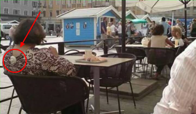 Answer: The lady sitting on the chair has a theft detector on her blouse!